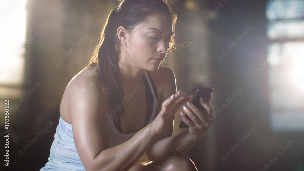 美丽的运动型深色皮肤在剧烈交叉健身后躺在长椅上使用智能手机