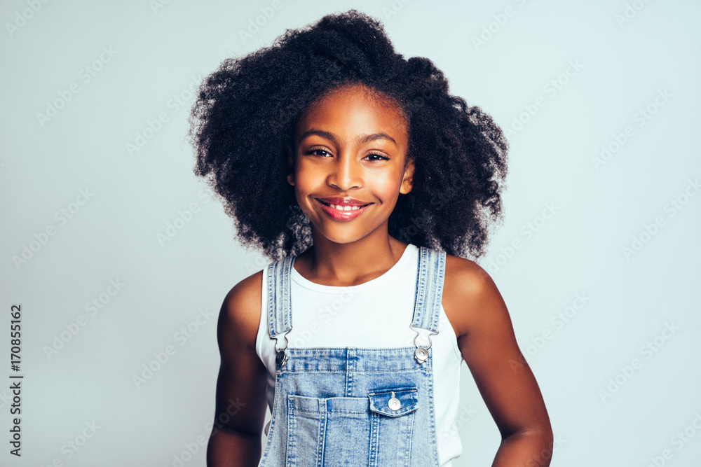 微笑的年轻非洲女孩穿着工装裤，灰色后背