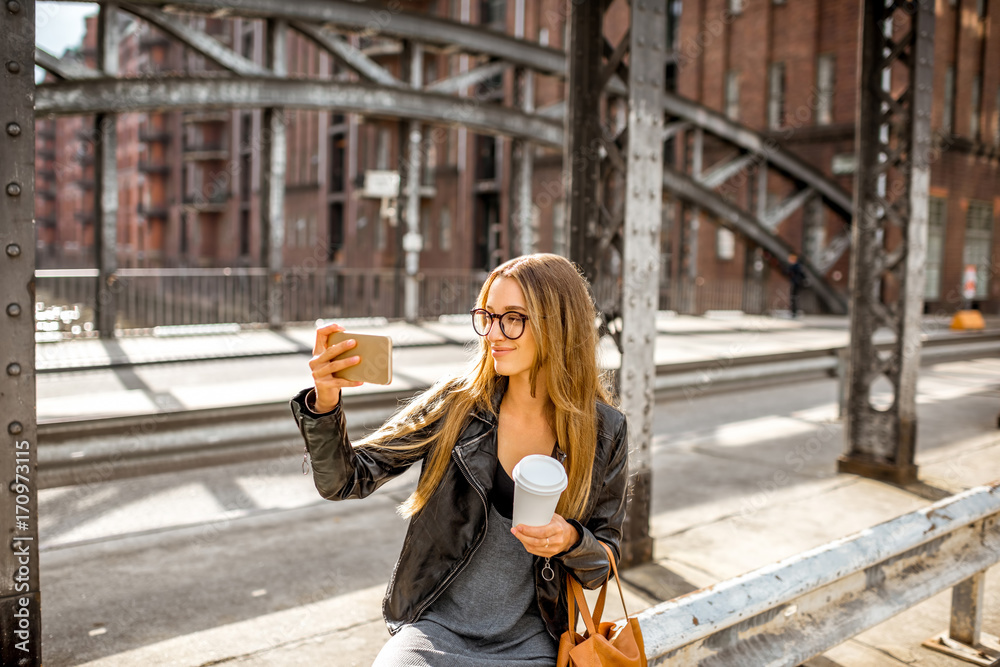 一位穿着皮夹克、拿着智能手机和咖啡的时尚女商人的生活方式画像
