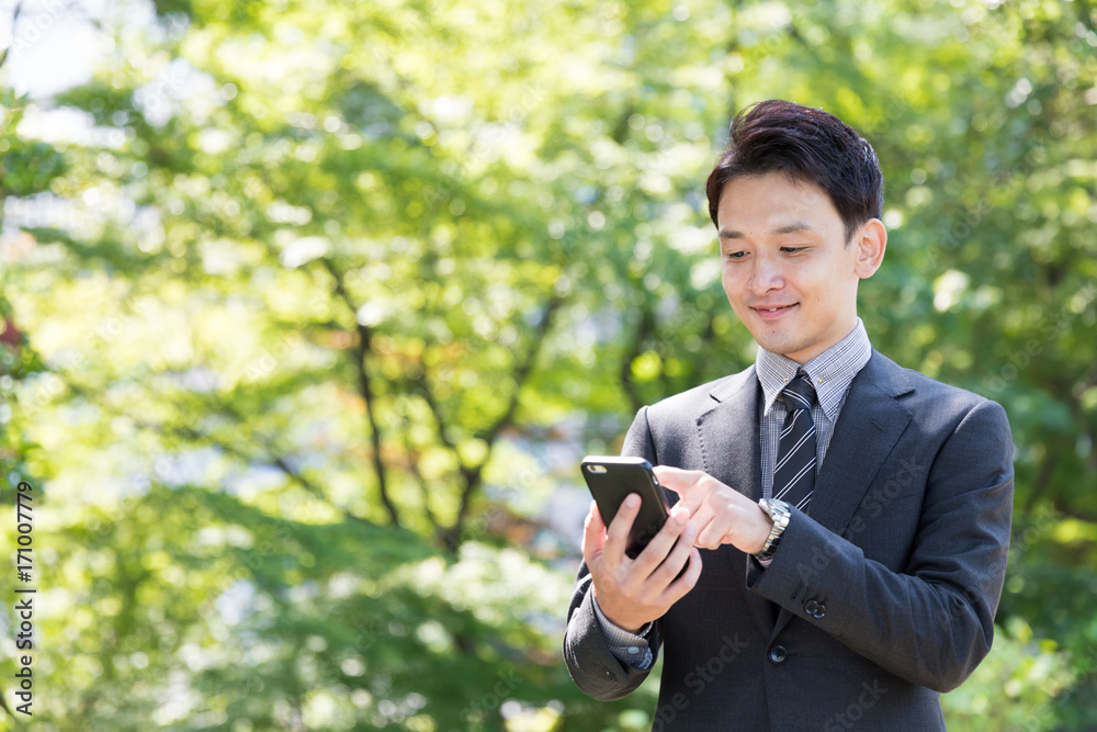 亚洲商人在公园里使用智能手机