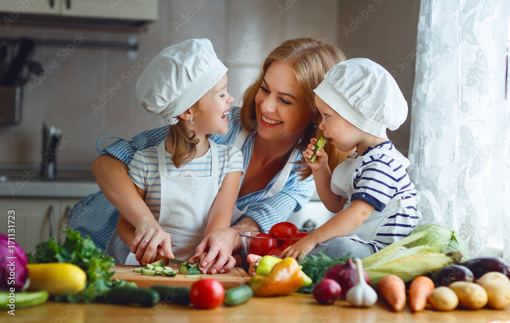 健康饮食。快乐家庭母亲和孩子在厨房准备蔬菜沙拉。