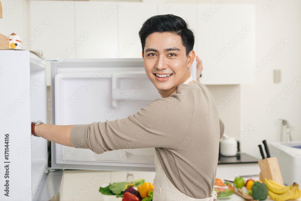 年轻的亚洲英俊男子在家厨房准备食物