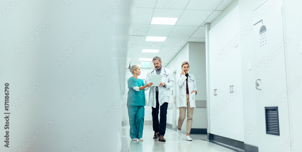 Group of medics with clipboard walking along hospital corridor