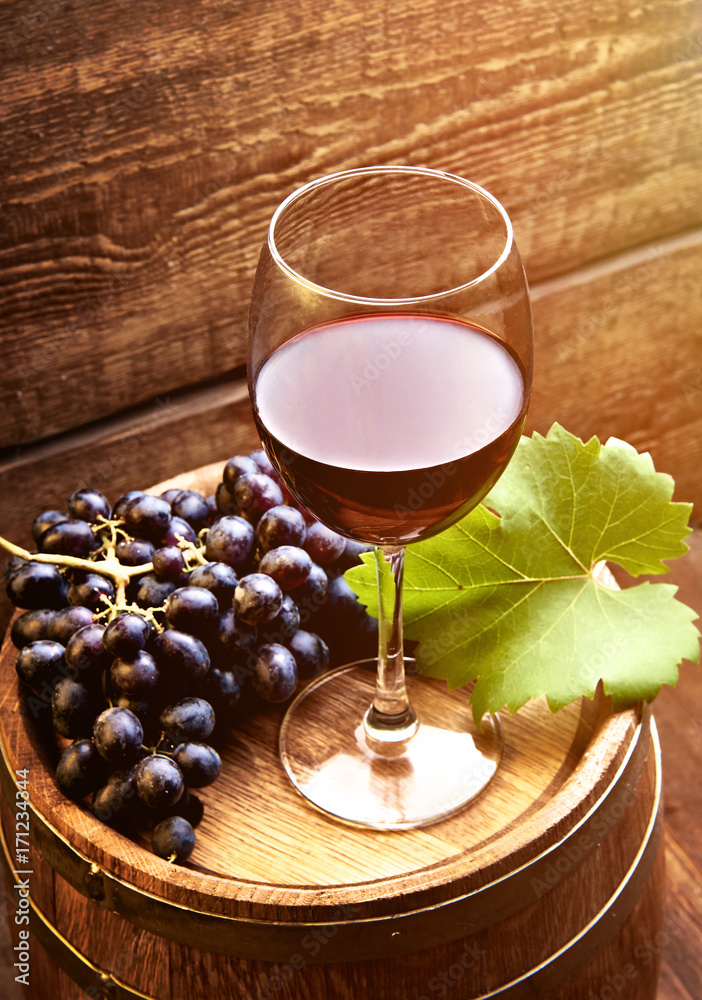 木桌上的一杯葡萄酒，里面有成熟的葡萄酒葡萄和木桶。