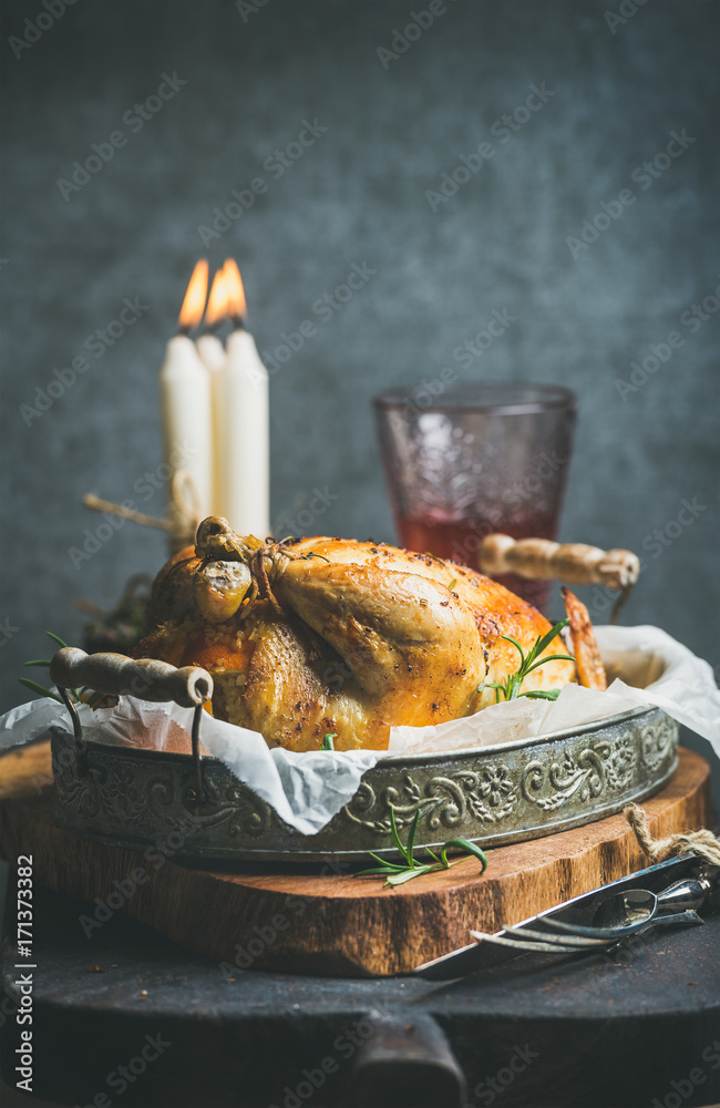 圣诞餐桌上摆着烤整只鸡，配橙子、保加利亚干酪和迷迭香，还有装饰蜡烛