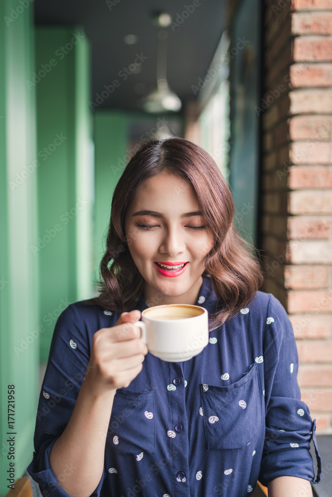 快乐的年轻商业女性的画像，手里拿着马克杯，早上在餐馆喝咖啡