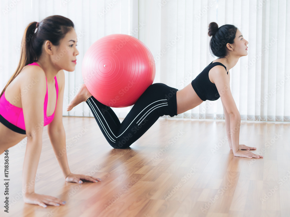 Women doing exercise with fit ball in gym class