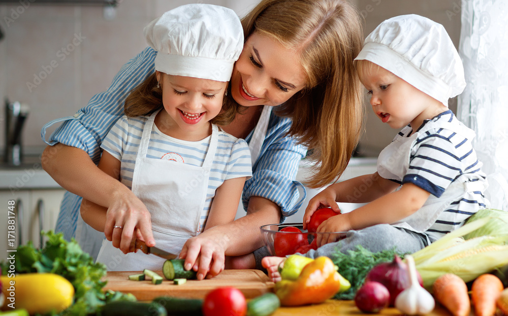 健康饮食。幸福的家庭母亲和孩子们在厨房准备蔬菜沙拉。