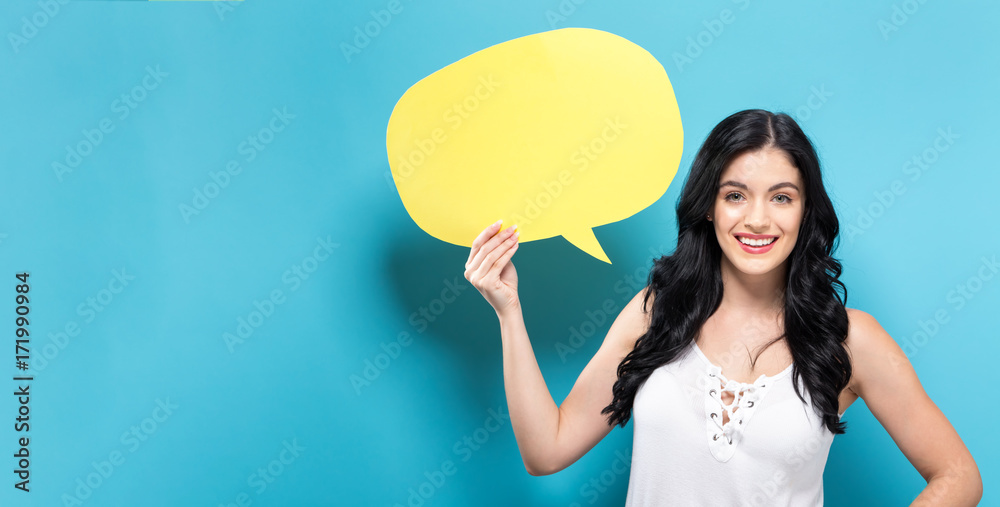 Young woman holding a speech bubble on a solid background