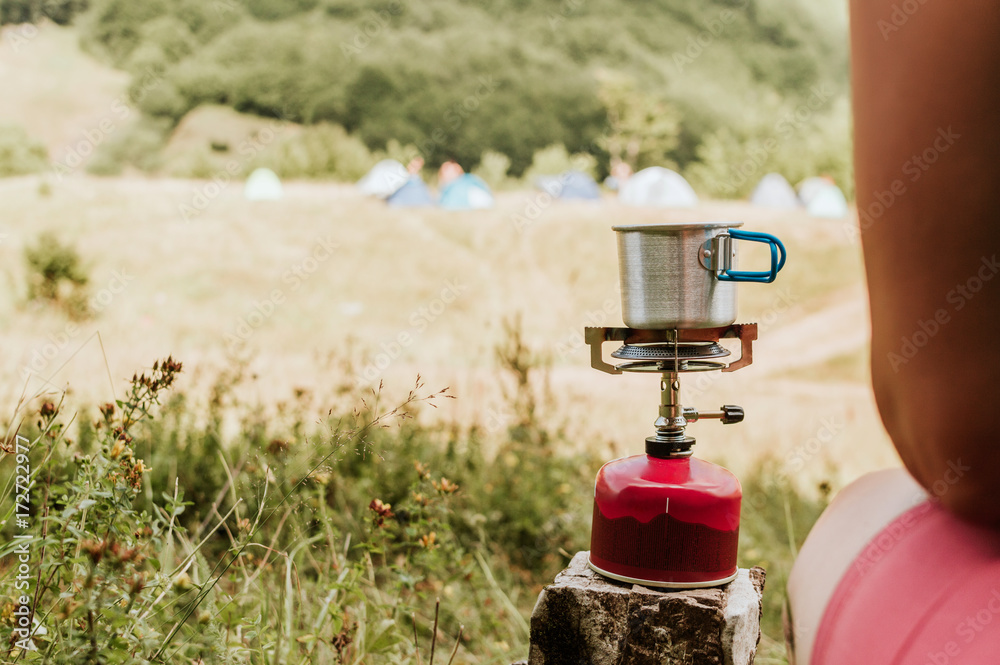 用便携式露营炉煮咖啡，露营概念。