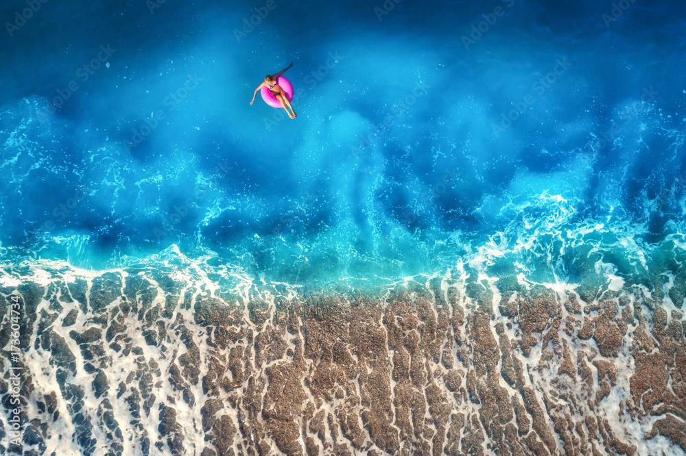 奥卢登透明绿松石海中一名年轻女子在粉色游泳圈上游泳的鸟瞰图