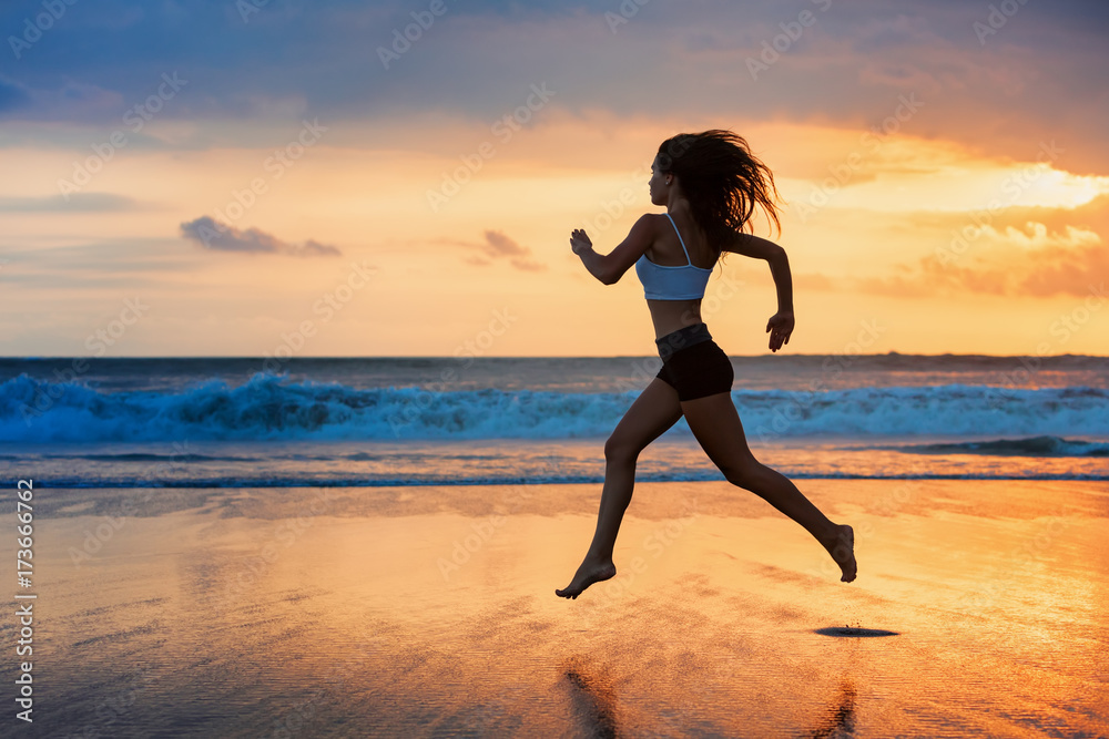 赤足运动女孩的侧影，沿着泳池边的海浪奔跑，保持身体健康。日落