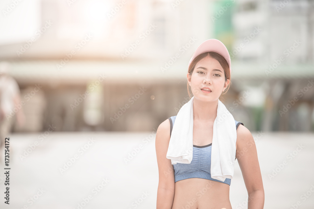 亚洲运动女性拿着毛巾在市中心慢跑和跑步