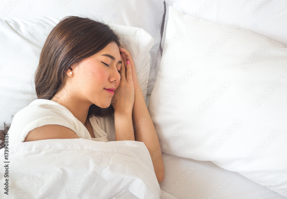 美丽的亚洲女人睡在白色的床上，心情愉快