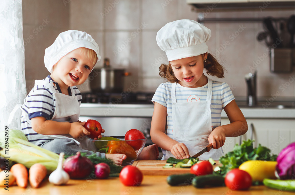 健康饮食。快乐的孩子在厨房准备蔬菜沙拉