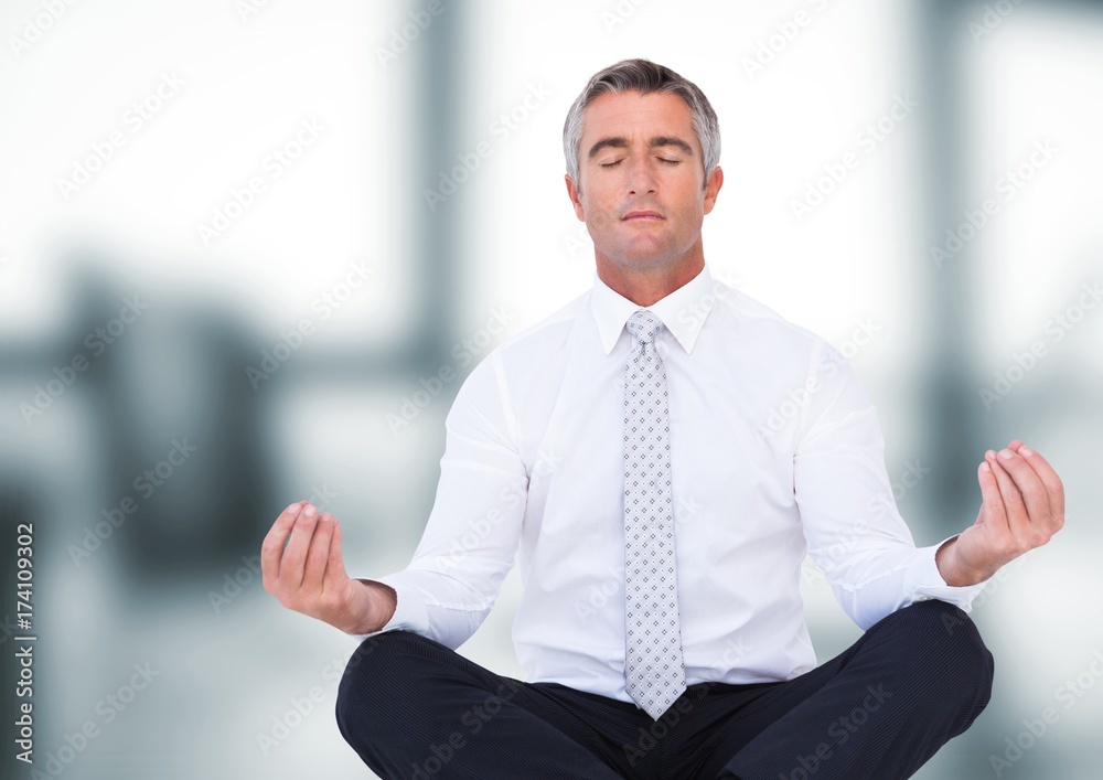 Business man meditating against blurry office