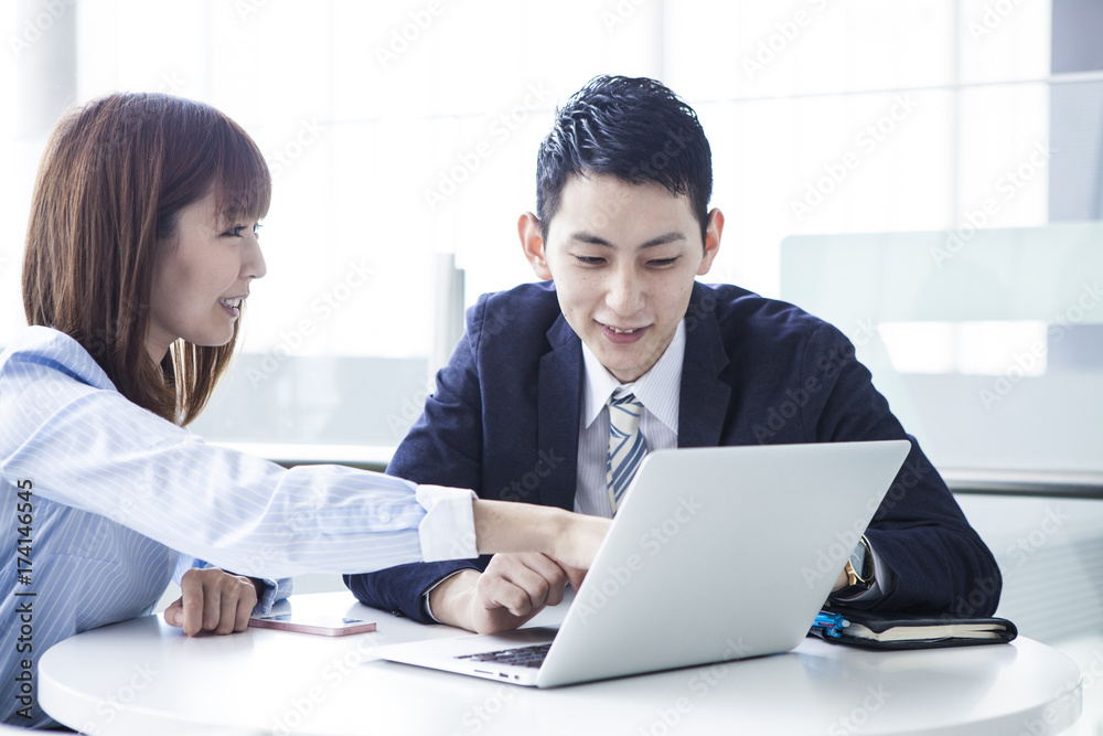 A business couple is talking while watching a personal computer