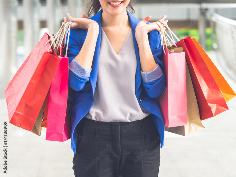 女性购物理念，亚洲女性在城市/购物中心拿着五颜六色的购物袋，微笑