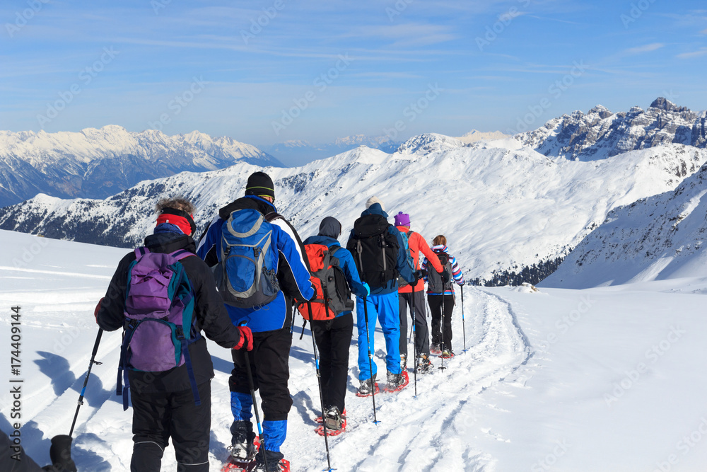 一群人穿着雪鞋徒步旅行，在奥地利斯塔拜阿尔卑斯山欣赏蓝天的山雪全景