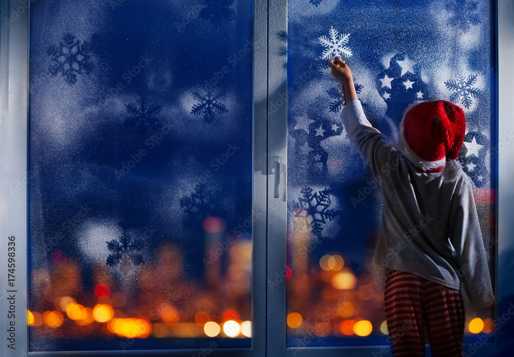 男孩用雪花装饰新年窗户