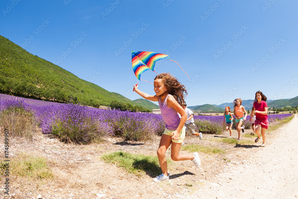 可爱的女孩带着风筝在薰衣草地里奔跑