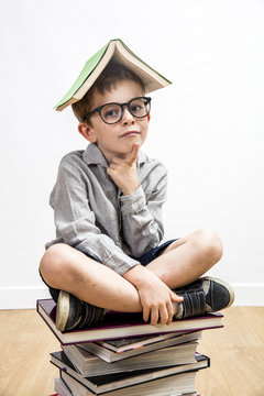 thoughtful smart child with book on head having education thoughts
