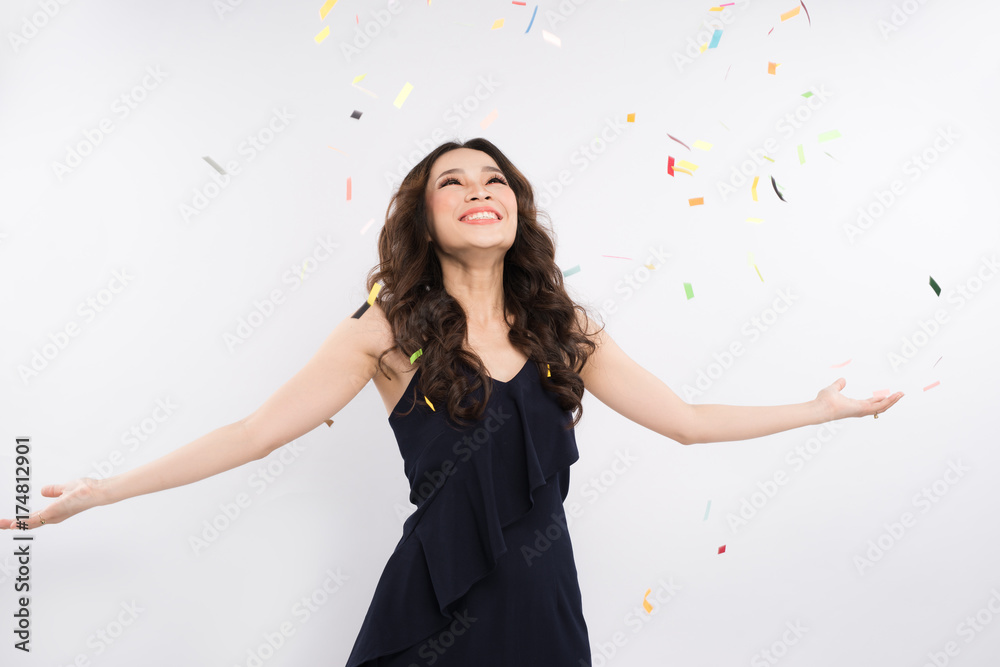 Beautiful asian woman with confetti falling everywhere on her. Birthday or New Year eve celebrating 