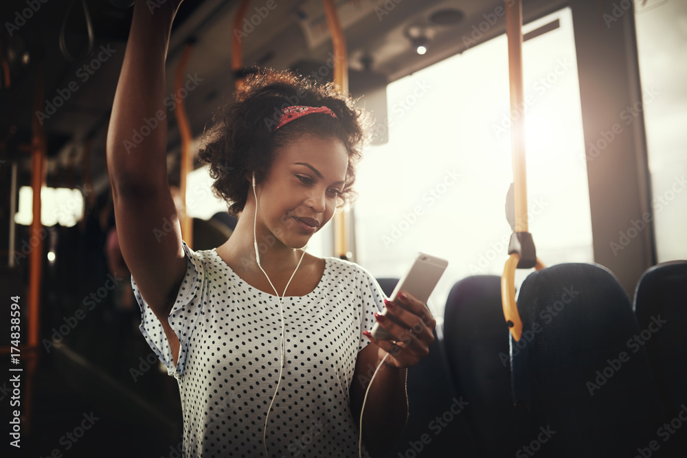微笑的非洲年轻女子在公交车上听音乐
