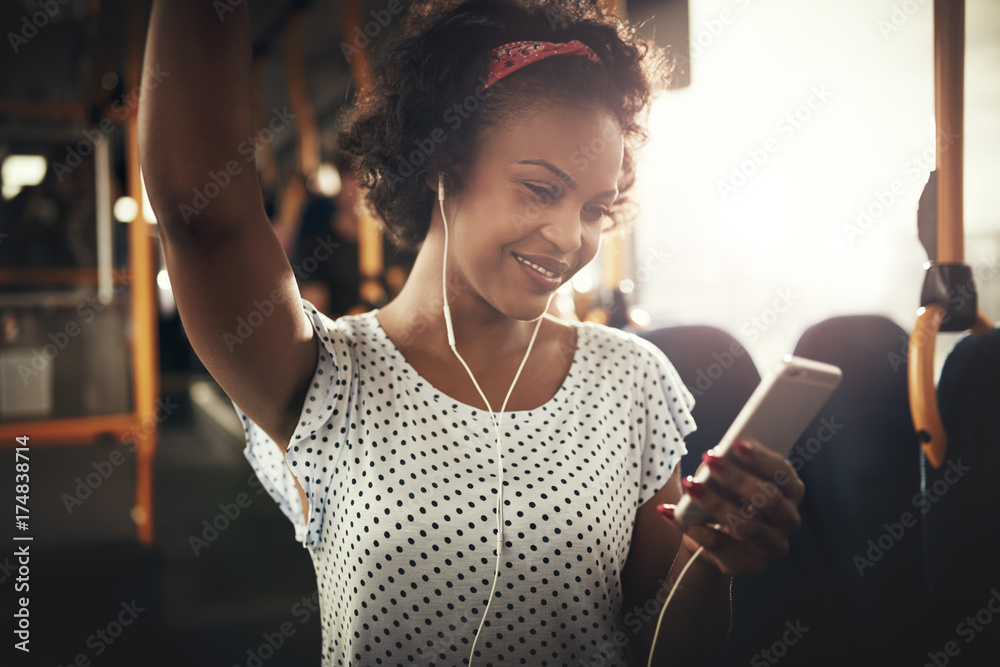 Smiling young African woman riding a bus listening to music