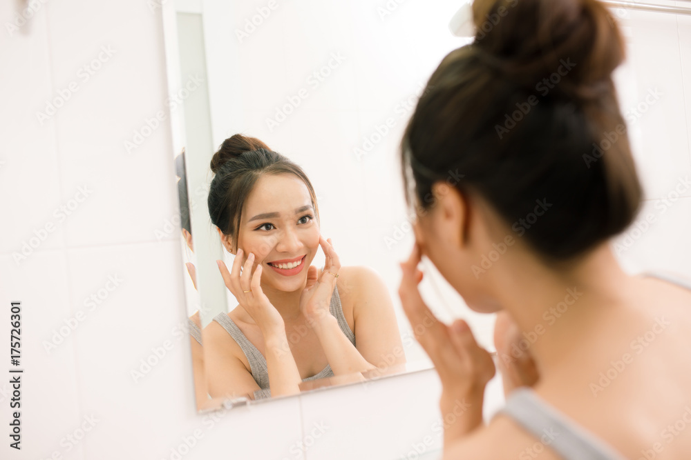 微笑的年轻女子在家里的浴室里对着镜子