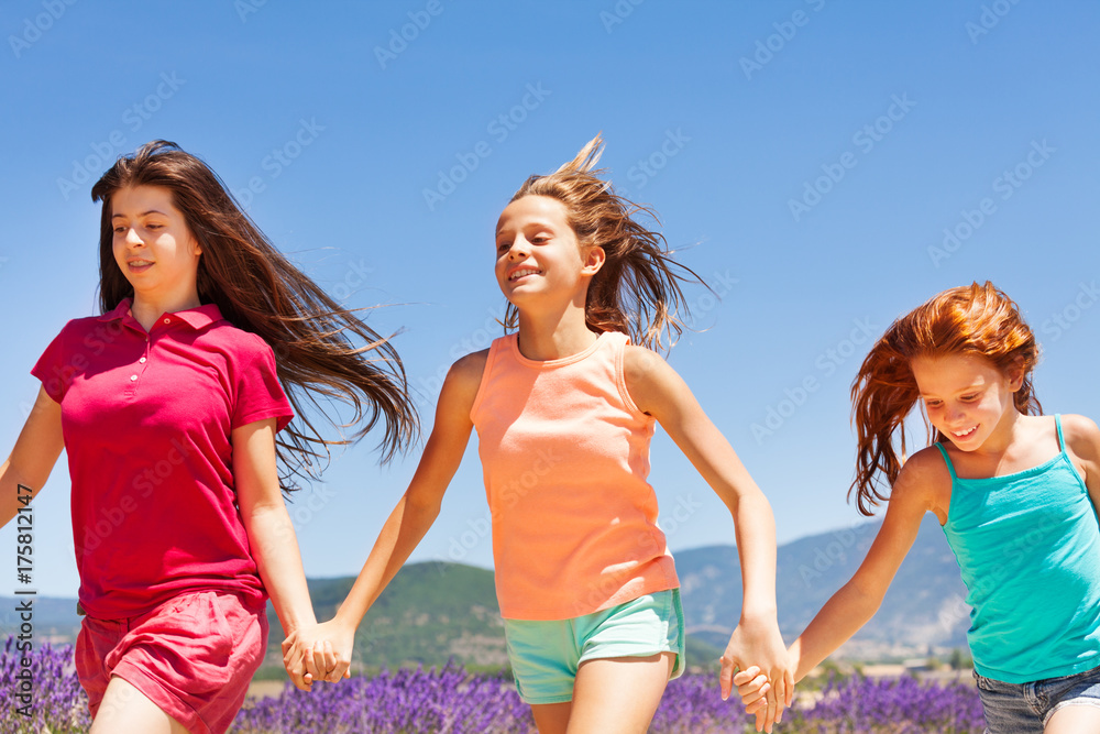 三个快乐的女孩一起在户外跑步