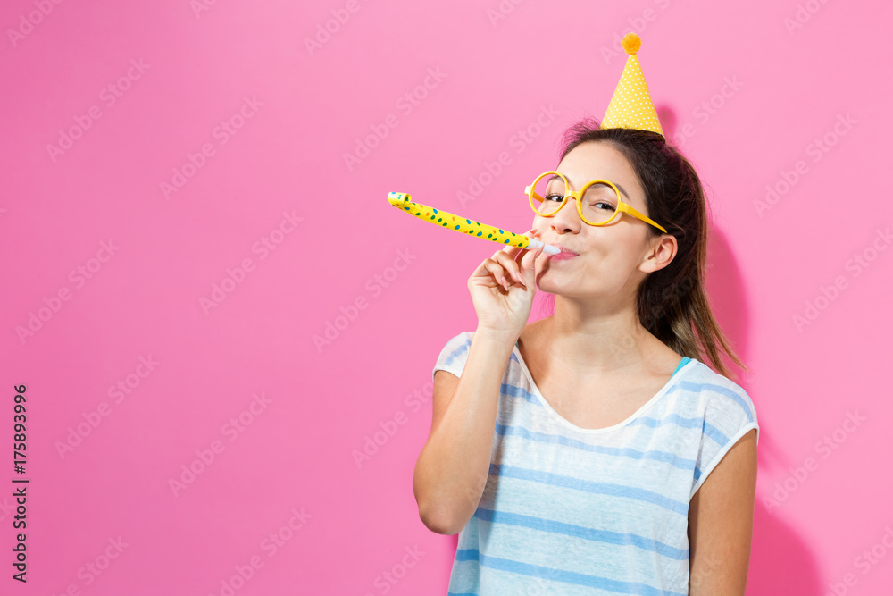 快乐的女人戴着粉色背景的派对帽庆祝