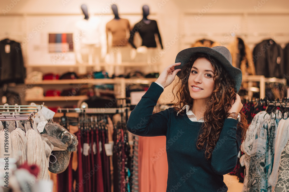 一名年轻成年女子在零售店试戴帽子。