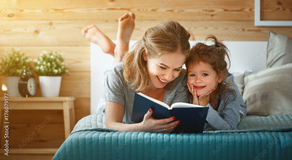 幸福的家庭母亲和女儿在床上看书。