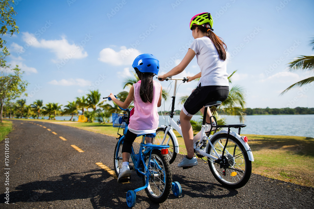 母亲和女儿早上在公园骑自行车。