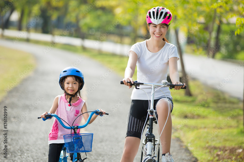 母亲和女儿正在骑自行车去公园
