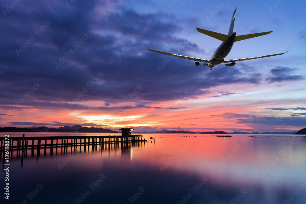 商业飞机在云层上方飞行，背景明亮，日落或日出时天空壮观。