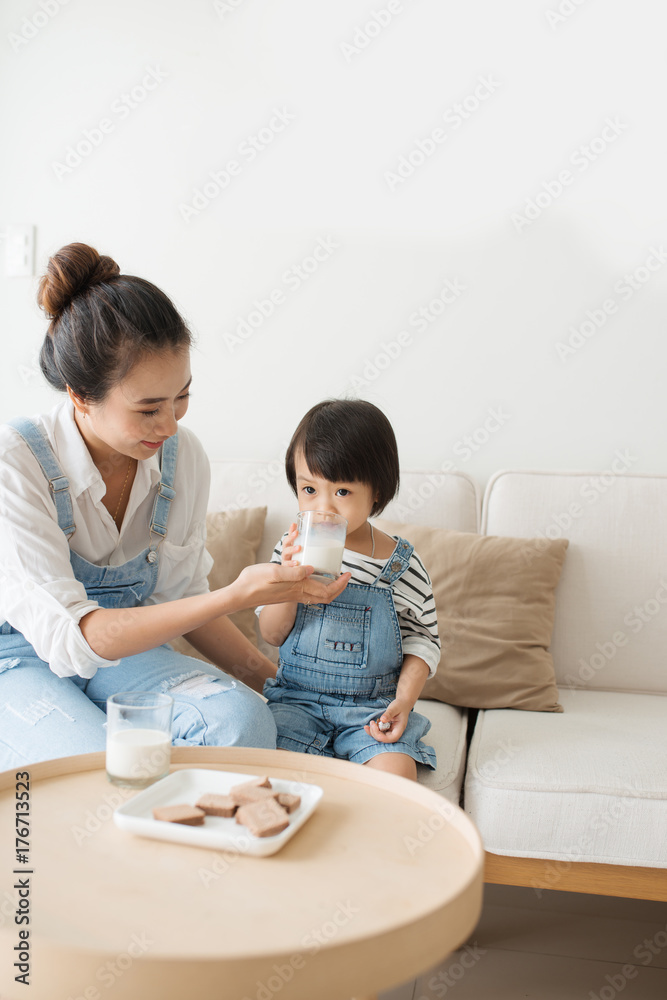 亚洲妈妈的幸福家庭早上在家和她可爱的女儿一起喝牛奶