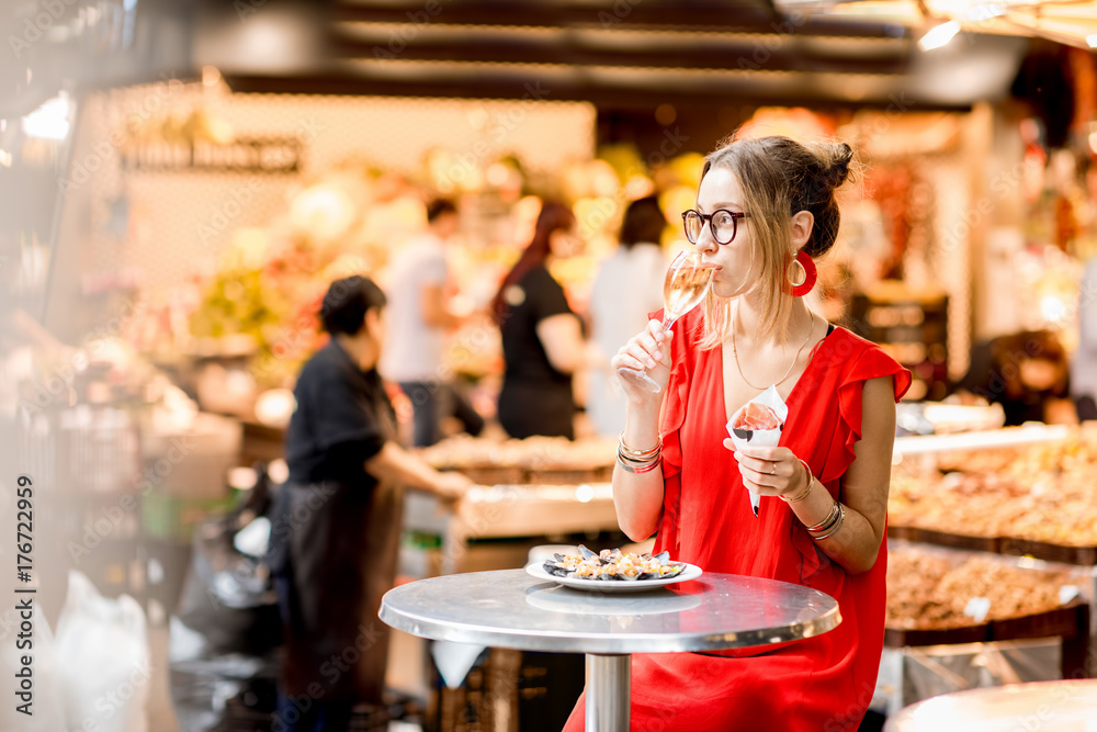 一名身穿红色连衣裙的年轻女子坐在巴塞罗那餐厅吃着传统的西班牙干腌火腿