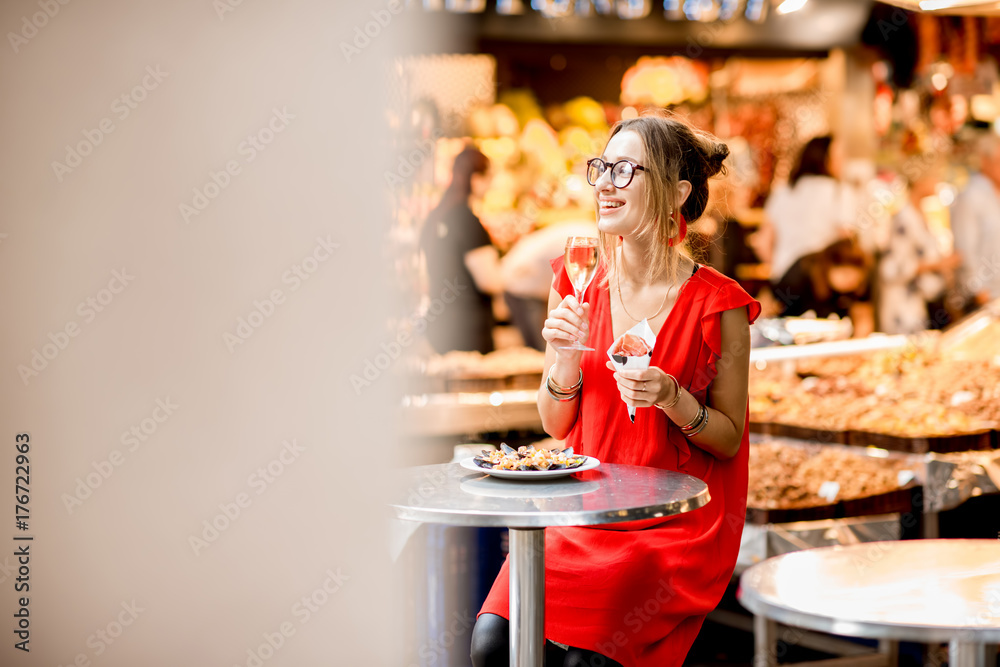 一名身穿红色连衣裙的年轻女子坐在巴塞罗那餐厅吃着果酱传统的西班牙干腌火腿