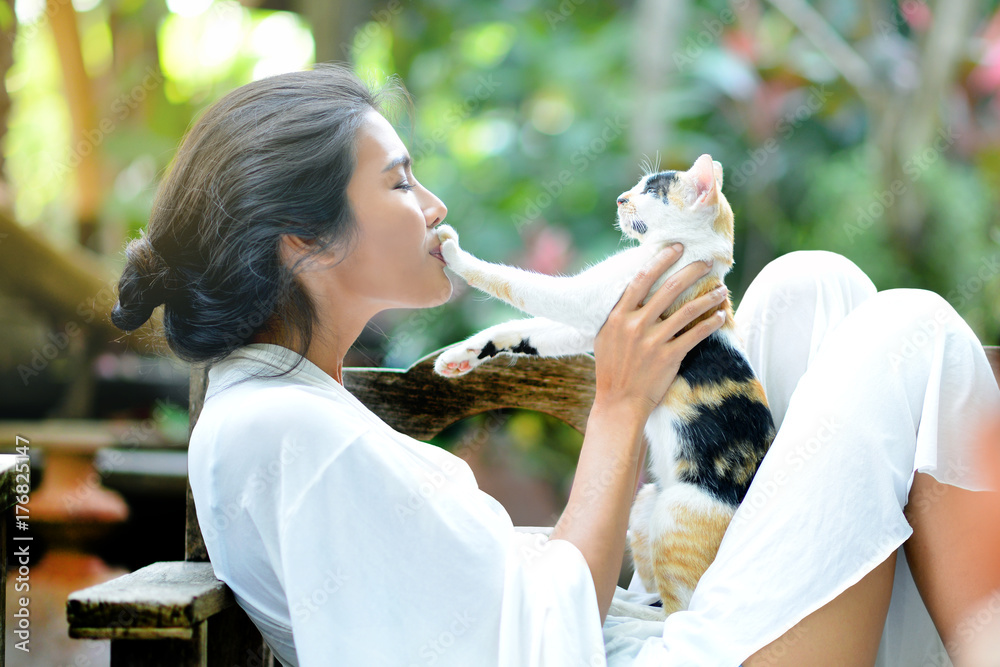 一名年轻女子和一只猫在花园的扶手椅上休息