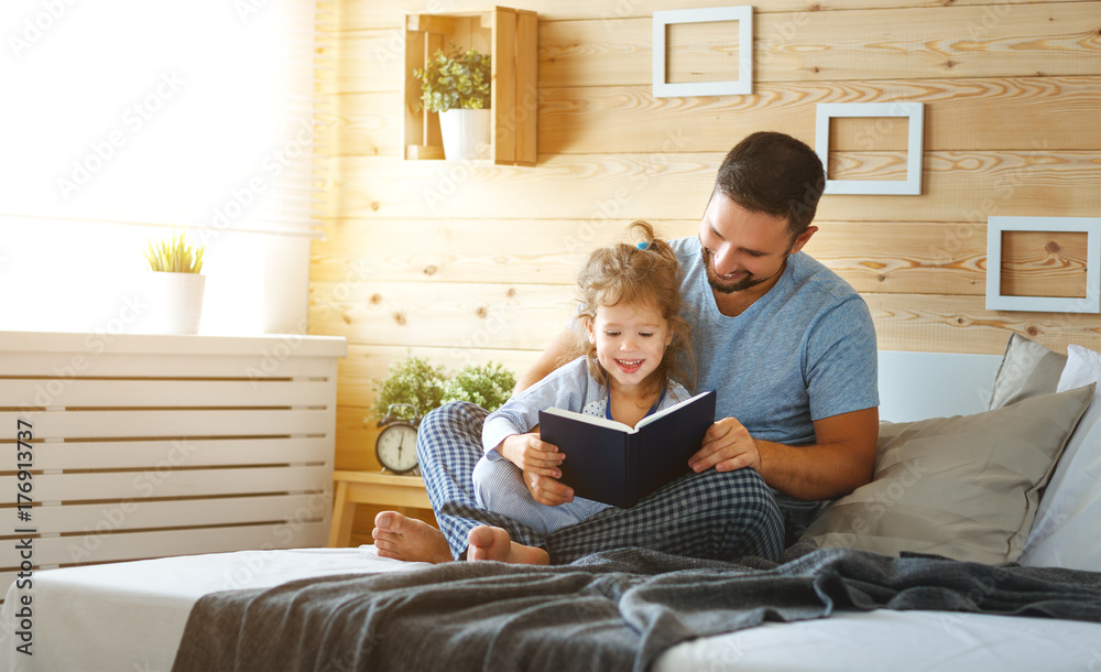 happy family father and daughter reading book in bed.