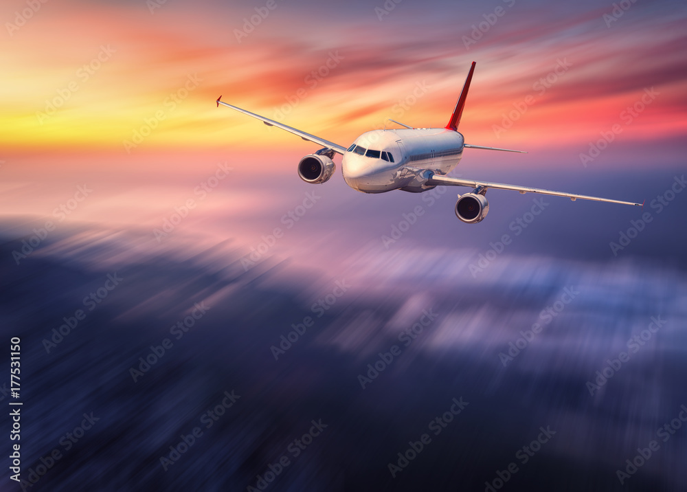 日落时，现代飞机的运动模糊效果在低云上飞行。风景如画