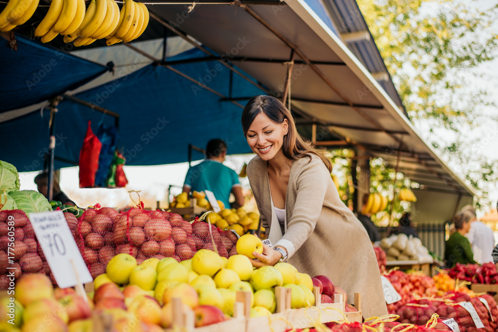 女人在市场上寻找水果和蔬菜。
