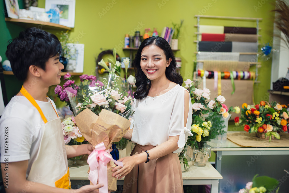 Florist giving bouquet of flower to woman in flower shop