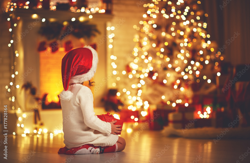 平安夜，一个女孩坐在圣诞树前