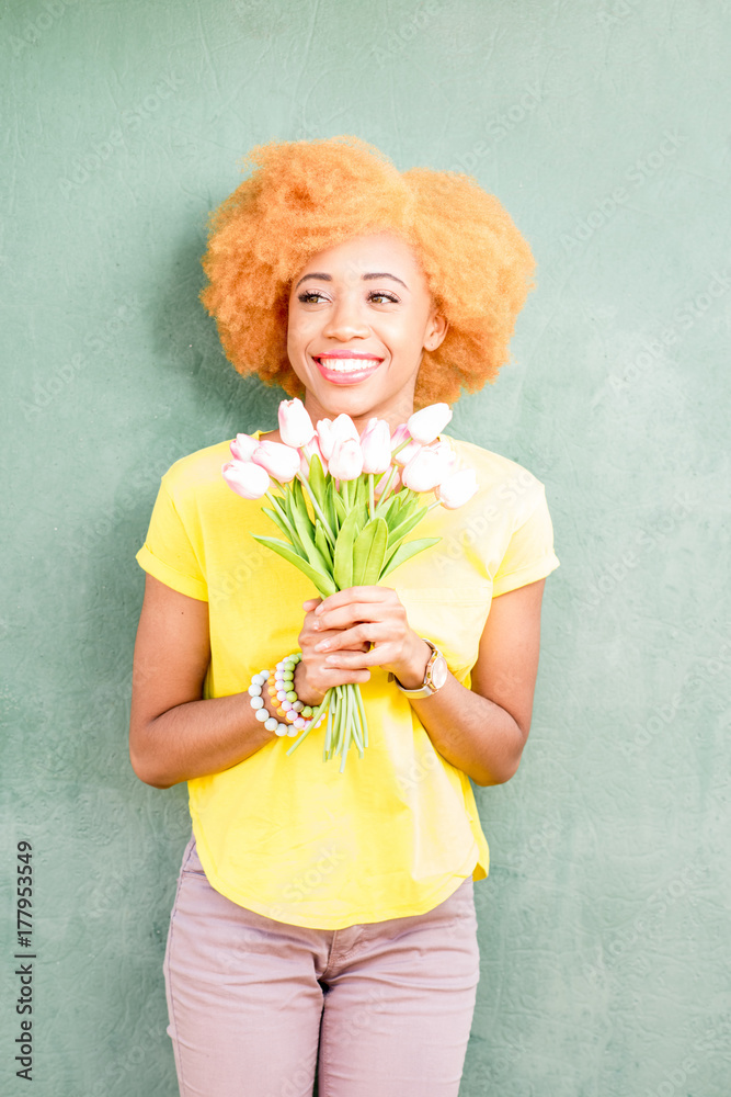 背景墙绿色墙上，一位美丽的非洲妇女手持一束郁金香的彩色肖像