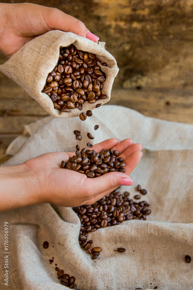咖啡粒从袋子里倒进手里。木质背景。