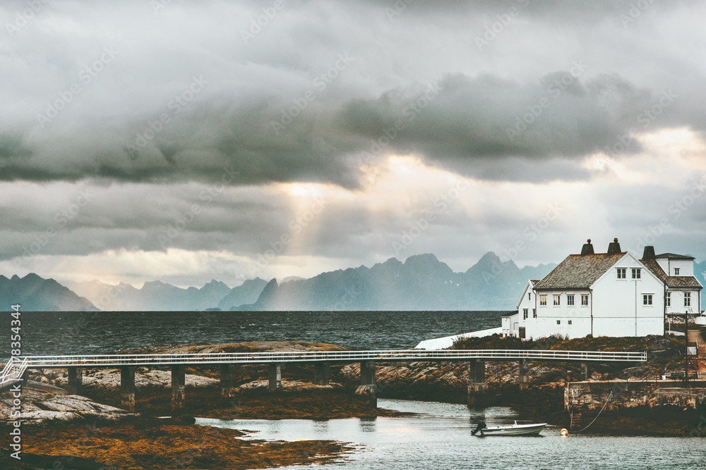 挪威风景日落时的白色传统房屋背景是大海和山脉旅游风景
