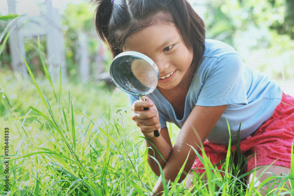 little girl with magnifying glass in nature